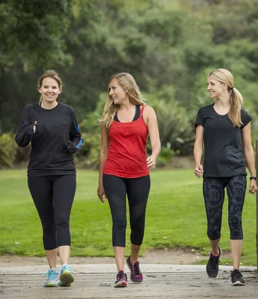 Three women walking on path.